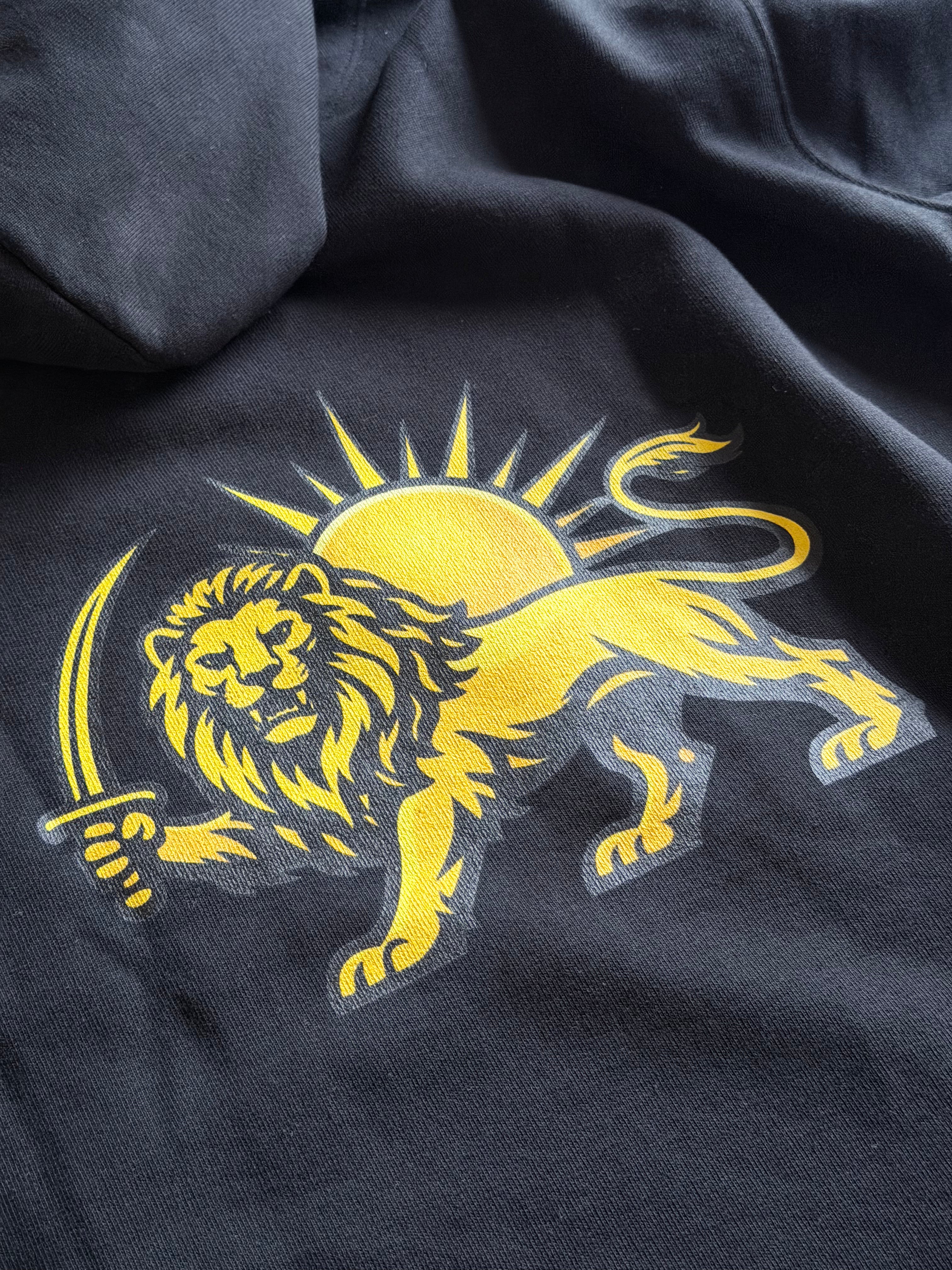 Close-up of a black hoodie featuring a large yellow lion graphic with a sword and a yellow sun behind it.
